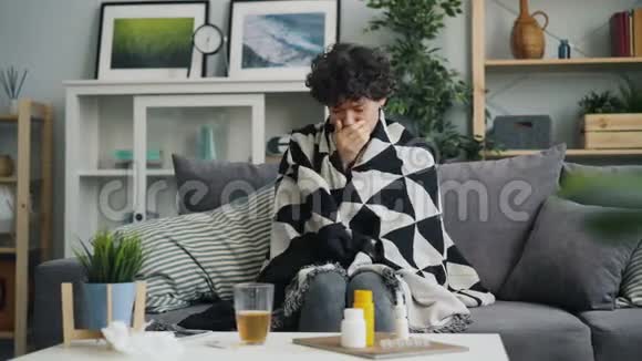 一位年轻女士在家里用毯子裹着身体咳嗽喉咙痛视频的预览图