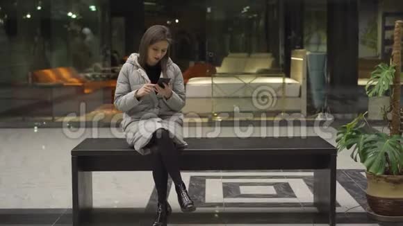 女孩在智能手机上滚动坐在长凳上和男朋友说话视频的预览图