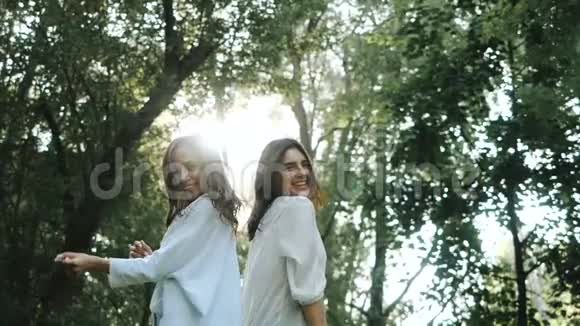 两个快乐的年轻黑发女孩在慢动作中欢笑和跳舞令人愉快的女人头发随风飘动视频的预览图
