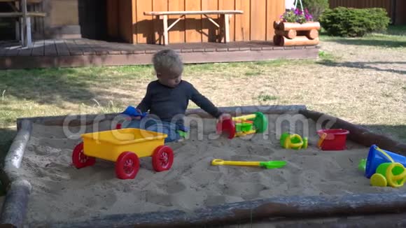 夏天兴奋的小男孩在沙箱沙坑里玩五颜六色的玩具视频的预览图