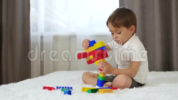 一个小男孩坐在一张床上的房间里和meccano玩视频的预览图