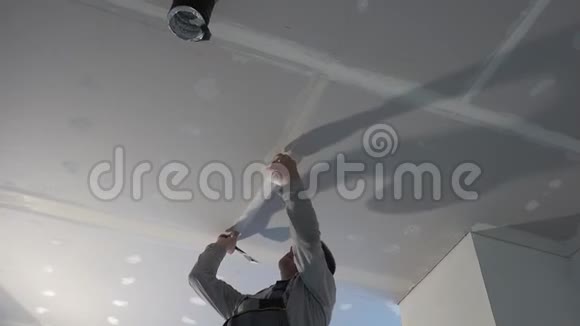 工人将玻璃纤维胶带粘在天花板石膏板上视频的预览图