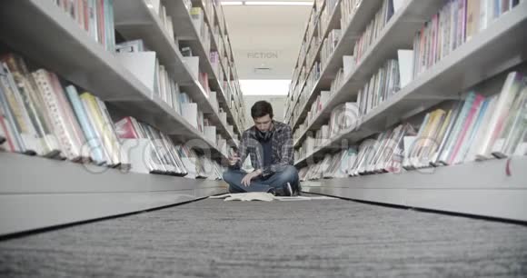 大学生坐在图书馆的地板上看书翻书页视频的预览图