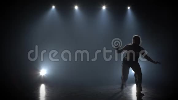 有长发的女人在黑暗中练习卡波伊拉对抗演播室的聚光灯视频的预览图