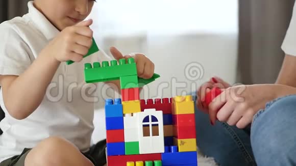 从梅卡诺的房子的特写一个女人和一个小男孩用彩色积木搭建一座房子体验情感视频的预览图
