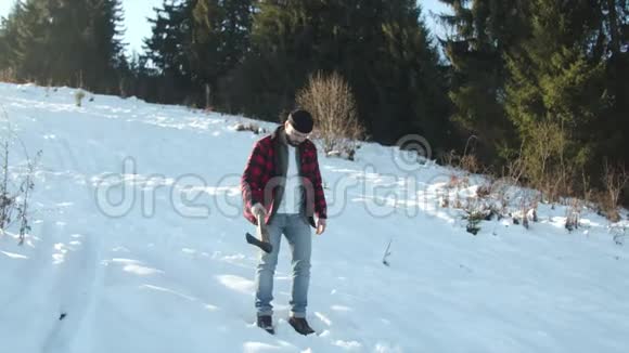野蛮的伐木工人带着斧头沿着雪坡前进视频的预览图