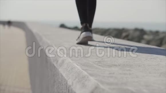 阳光明媚的一天一个运动女孩沿着海滨的城市长廊散步视频的预览图