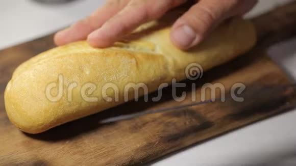 男人用锋利的刀在厨房的木板上把面包切成两半用西班牙果酱做三明治视频的预览图
