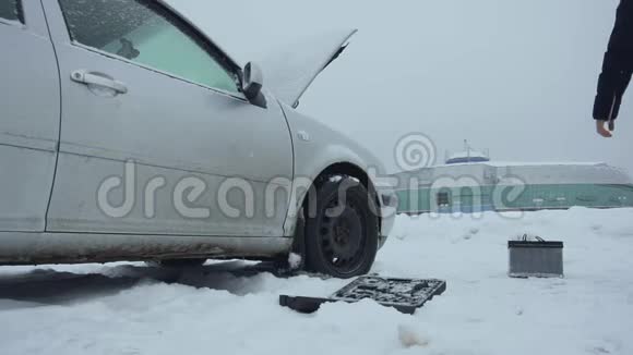 人类在冬天从积雪覆盖的地面上举起汽车电池并把它带到汽车上一次修理或修理视频的预览图