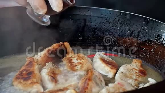 在平底锅中的煎饺上倒入酱汁视频的预览图