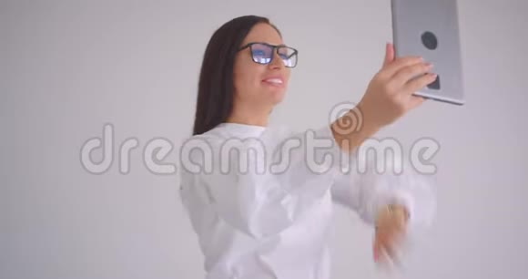 戴着眼镜的年轻漂亮的白种人女商人的特写肖像在平板电脑上播放视频视频的预览图