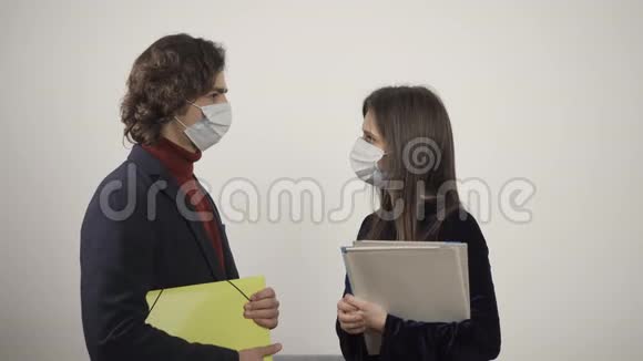 戴着医疗面具的年轻男女手里拿着文件夹互相交谈互相看着视频的预览图