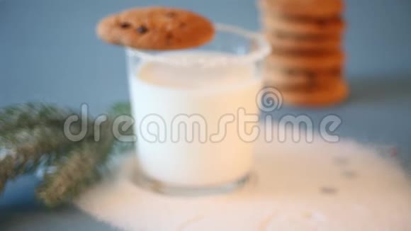 女人手把一杯牛奶放在蓝色的桌子上上面放着圣诞饼干圣诞树树枝视频的预览图