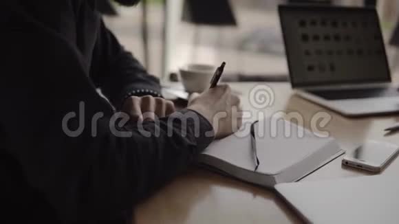 商人的手有一个人的最高视野笔和笔记本坐在咖啡馆的木桌上视频的预览图