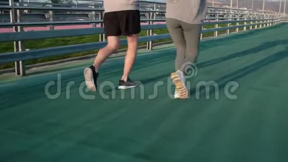 男子和妇女在露天体育场奔跑的腿后视视频的预览图