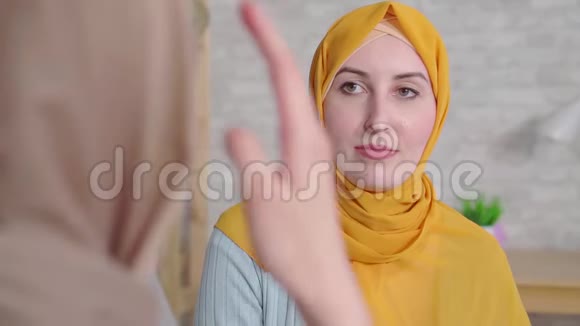 一张漂亮的笑脸一个聋的年轻穆斯林妇女戴着头巾在客厅里用手语说话视频的预览图