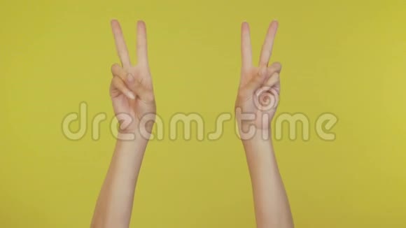 女人的手挥动着跳舞的手指拍打着音乐节奏的手势在工作室里的黄色背景上被隔离开来副本视频的预览图