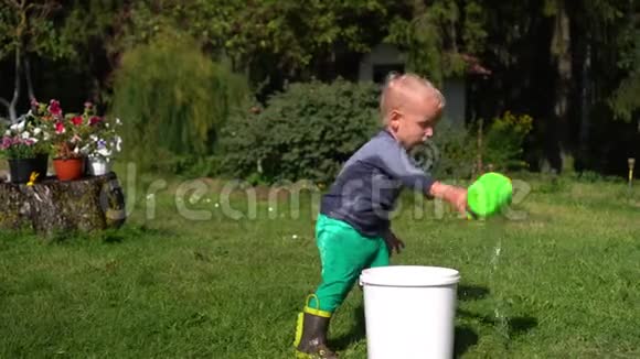 两岁的男孩在花园里玩水湿孩子给自己泼水视频的预览图