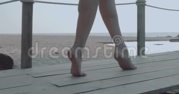 近距离女性双脚在沙滩和海底的小木桥上行走视频的预览图
