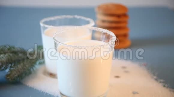 女人手把圣诞饼干放在牛奶杯上背景上的圣诞树树枝视频的预览图