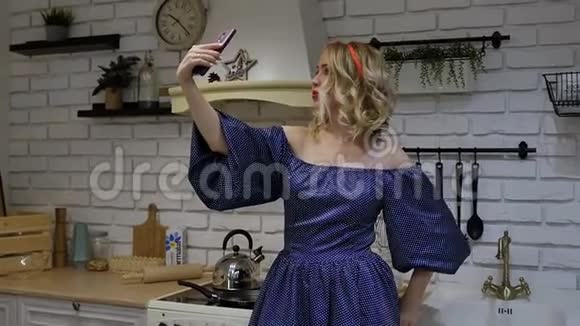 漂亮的年轻女孩子在厨房的智能手机上自拍慢动作视频的预览图