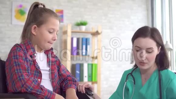 医生在诊所检查一名坐轮椅的残疾少女的腿视频的预览图