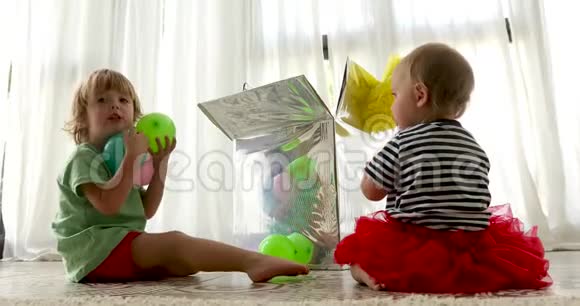 可爱的孩子坐在地板上玩五颜六色的气球视频的预览图