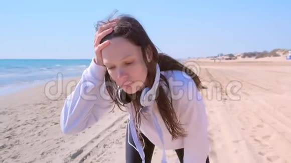 女孩停止慢跑呼吸运动跑步训练海沙海滩耳机视频的预览图