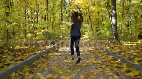 在阳光下的秋天公园里一个小女孩在小径上奔跑视频的预览图