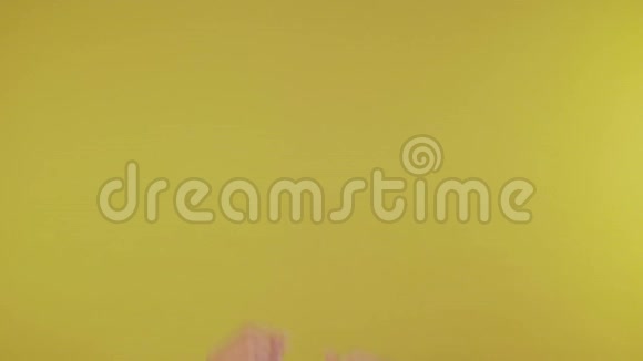 女人的手在黄色背景上拍打手指视频的预览图