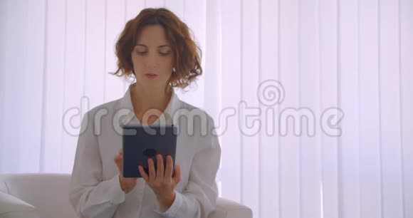 使用平板电脑拍摄白种人成年女商人的特写肖像并在镜头中显示绿色屏幕视频的预览图