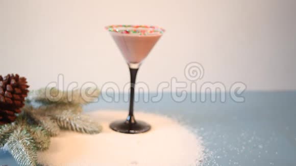 女人手把一杯冬令巧克力鸡尾酒放在蓝桌上上面放着圣诞树枝松果和雪像视频的预览图