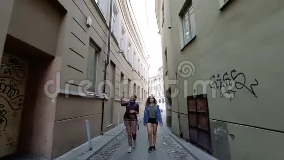 两个年轻的女人在维尔纽斯老城狭窄的街道上走来走去谈笑风生视频的预览图