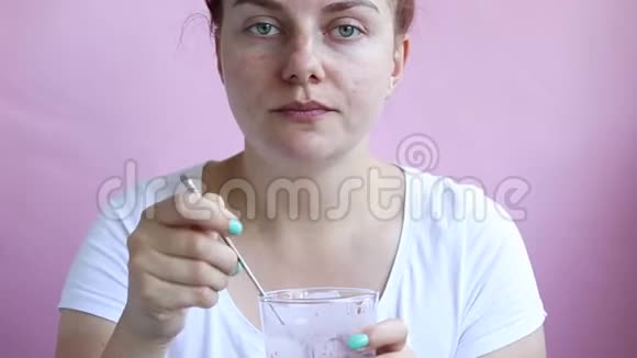 年轻的女孩拿着一杯带有天然酸奶新鲜覆盆子蜂蜜的麦片吃她的早餐视频的预览图