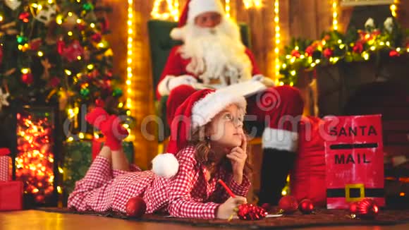 帕贾马的滑稽女孩圣诞帽在圣诞树附近给圣诞老人写信视频的预览图