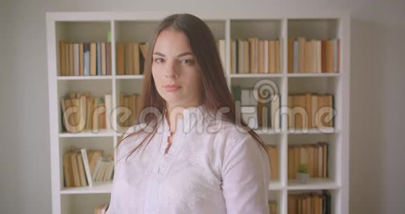 年轻漂亮的白种人女学生用双臂交叉在室内的胸部看镜头的特写镜头视频的预览图