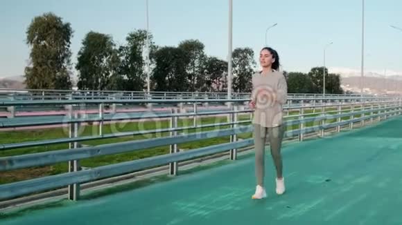 斯利姆女孩在阳光明媚的日子里在球场跑道上慢跑视频的预览图
