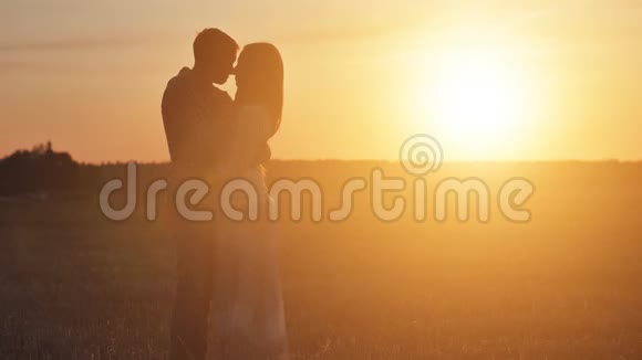 一对相爱的夫妇在夕阳背景下拥抱的剪影视频的预览图