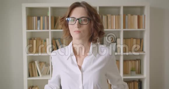 戴眼镜的白种人成年女商人用双臂交叉在胸前看镜头的特写照片视频的预览图