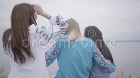 三个穿着夏日长礼服的年轻女朋友在湖边或视频的预览图