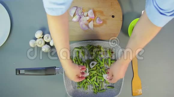 一个女人手把切好的洋葱放进一个装有青豆的锅里视频的预览图