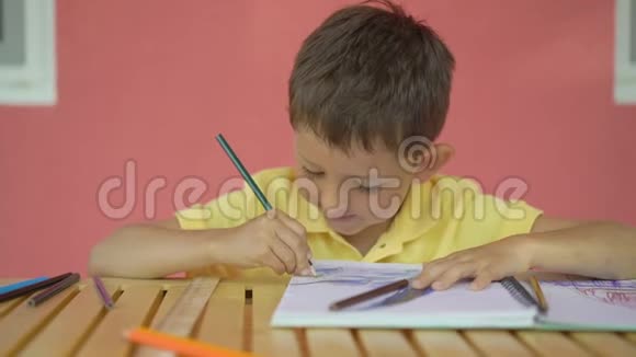 可爱的小男孩在木桌上的相册里画画视频的预览图