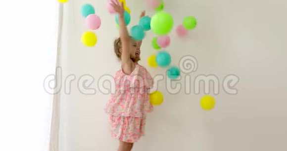 穿着粉色裙子的快乐笑女撒着五颜六色的气球视频的预览图