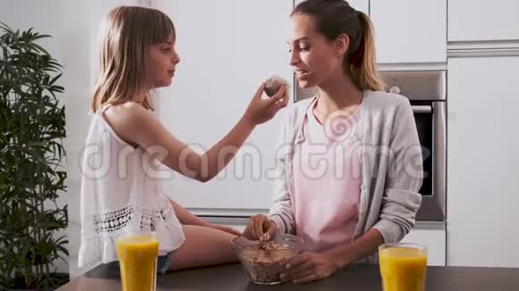漂亮的年轻母亲和女儿在家吃早餐时享受时光视频的预览图