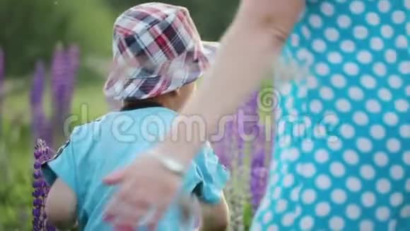 母亲和儿子带着鲜花在田野里奔跑和玩耍视频的预览图