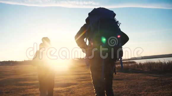 两名游客一起背着背包慢动作行走在阳光下剪影生活方式阳光照耀视频的预览图