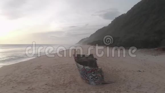 坐在沙滩上的船残骸上的女孩视频的预览图