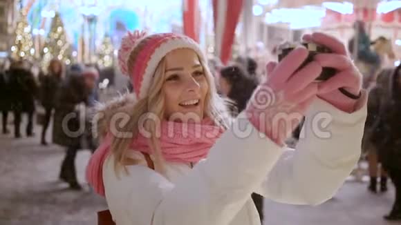 雪夜冬季市场上有复古相机的年轻女子自拍视频的预览图