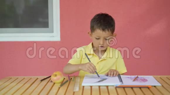 可爱的小男孩在木桌上的相册里画画视频的预览图