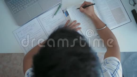 顶部视图印度学生准备考试时坐在桌前的笔记本电脑视频的预览图